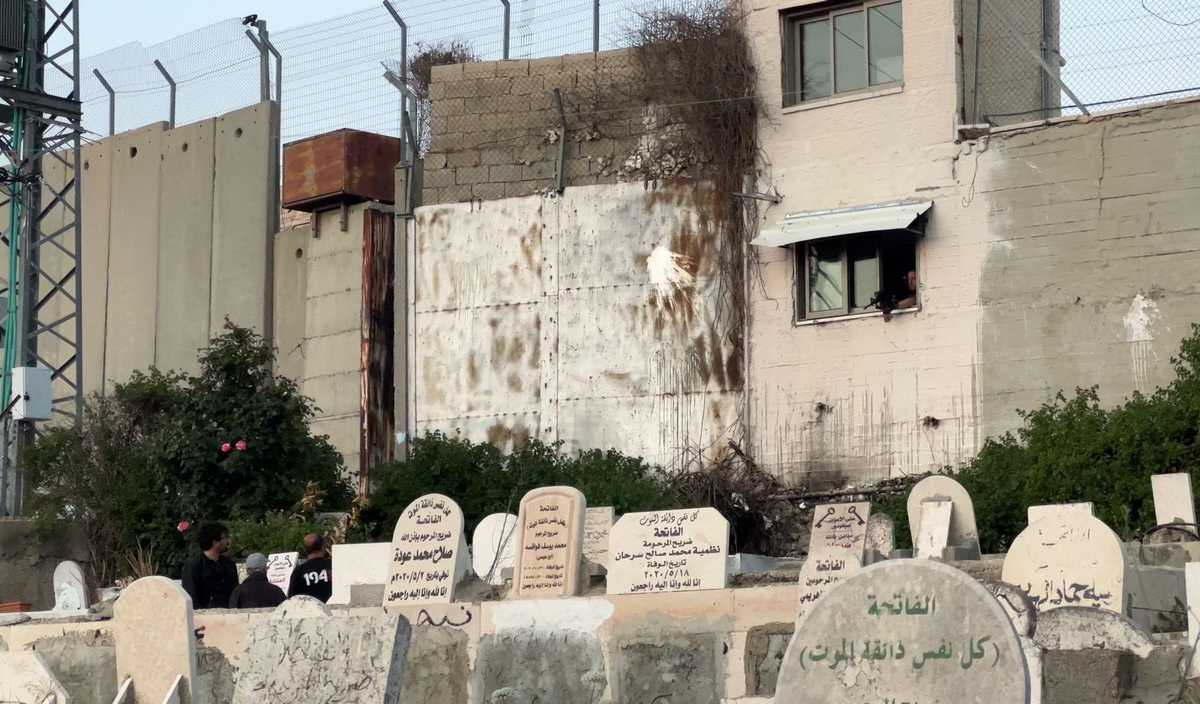 Um soldado da ocupação israelense ameaça a delegação do PI sob a mira de uma arma durante visita a um cemitério local.