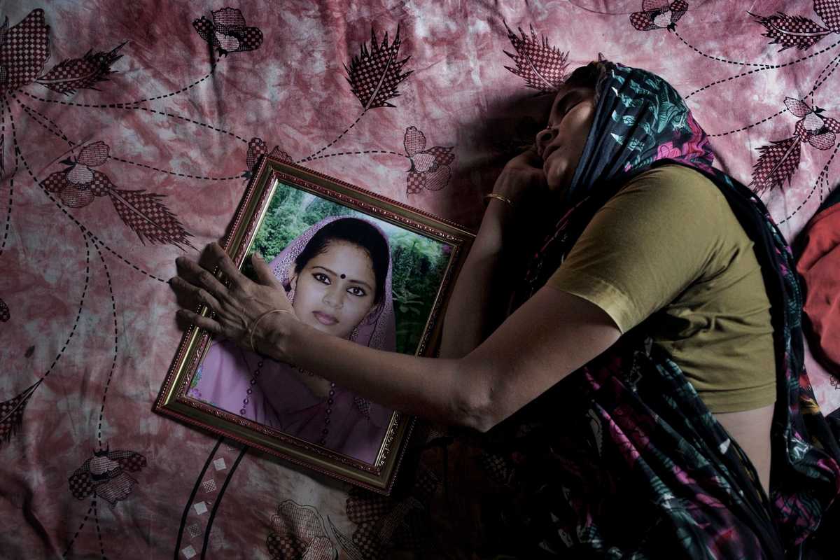 Mother grieves as she lies besides a photograph of her daughter Poly Akther, a garment factory worker who lost her life in the Rana Plaza collapse. Image: Taslima Akhter