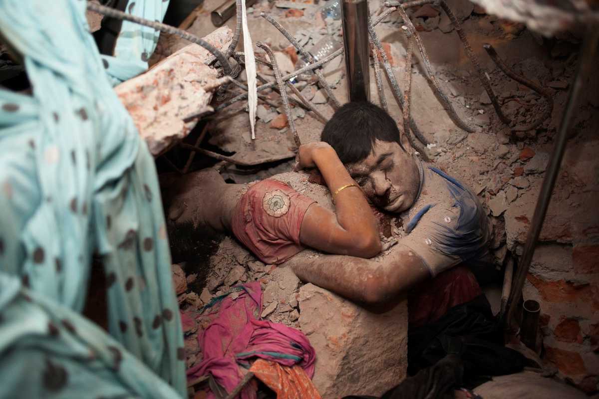 "Abrazo final": dos trabajadorxs entre los escombros del derrumbe de la fábrica de confecciones de Rana Plaza. Intentaron salvarse mutuamente en los últimos momentos de sus vidas. Unos 1175 trabajadorxs murieron y varios cientos desaparecieron en este edificio de ocho plantas. Savar, Dhaka, Bangladés. 25 de abril de 2013. Imagen: Taslima Akhter.